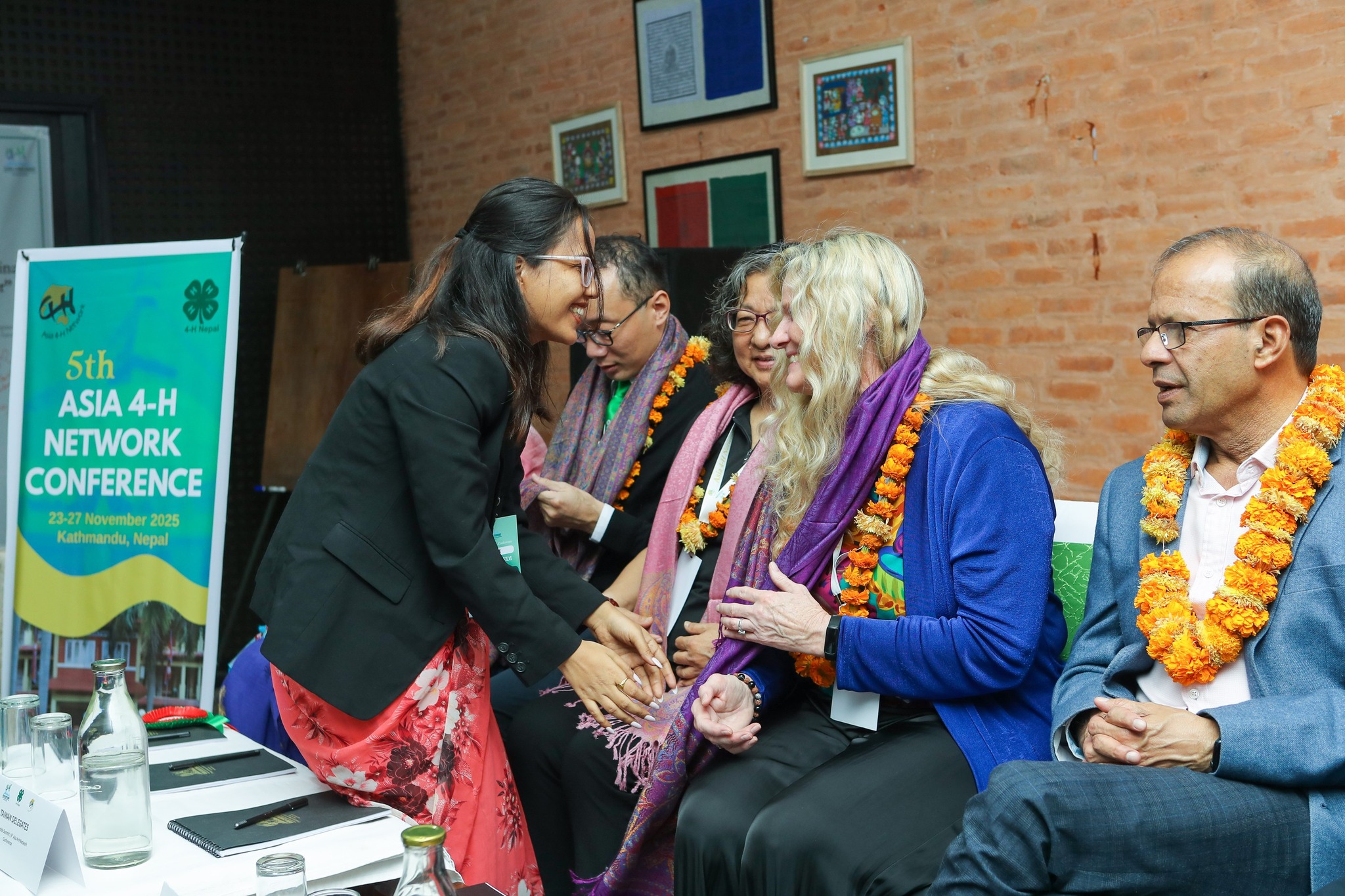 A row of people sitting with one woman's hand being shaken.
